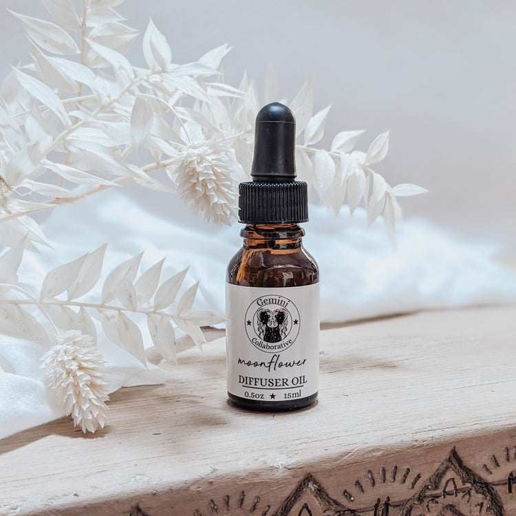 Photo of diffuser oil in half ounce glass bottle with glass pipette in front of floral arrangement