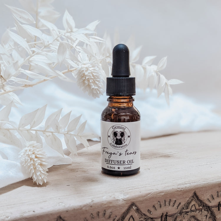 Photo of diffuser oil in half ounce glass bottle with glass pipette in front of floral arrangement