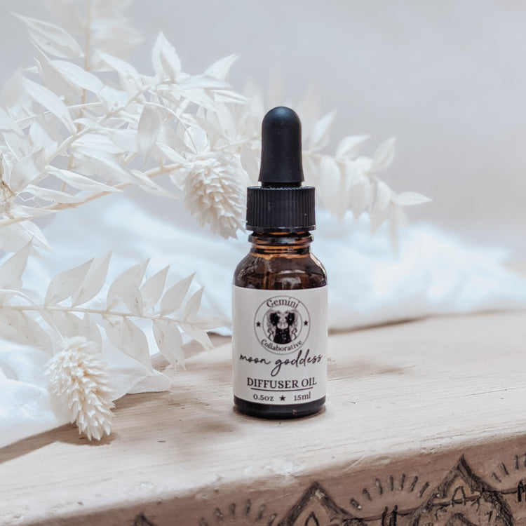 Photo of diffuser oil in half ounce glass bottle with glass pipette in front of floral arrangement