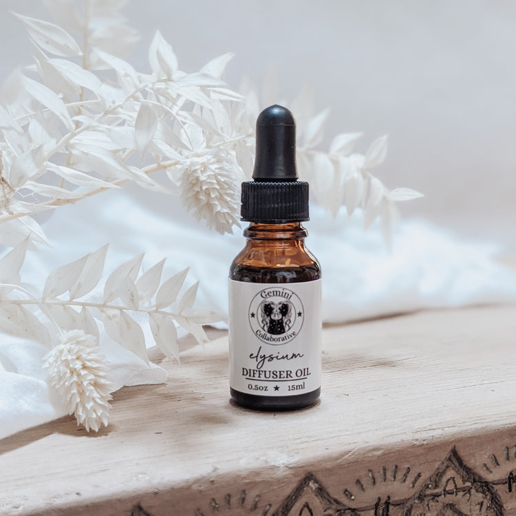 Photo of diffuser oil in half ounce glass bottle with glass pipette in front of floral arrangement