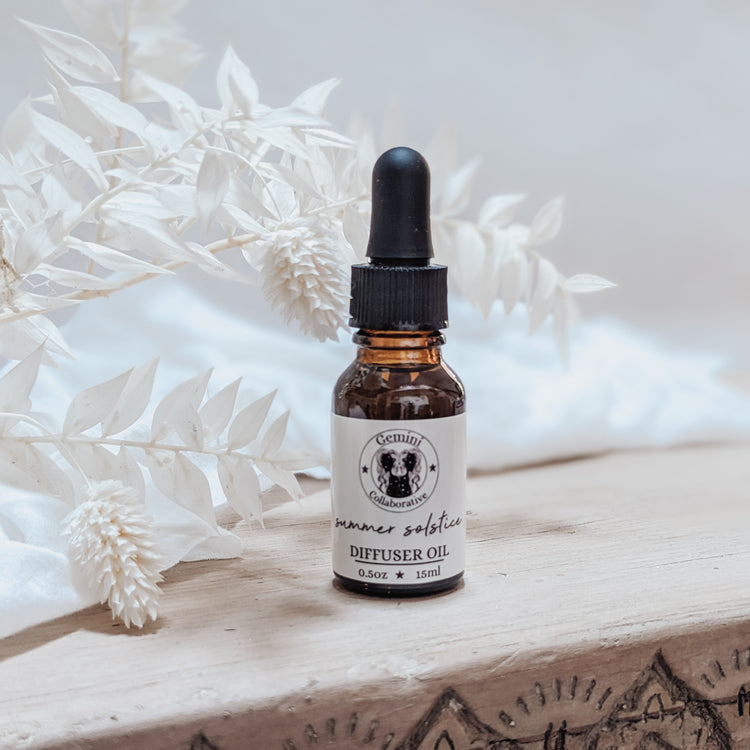 Photo of diffuser oil in half ounce glass bottle with glass pipette in front of floral arrangement