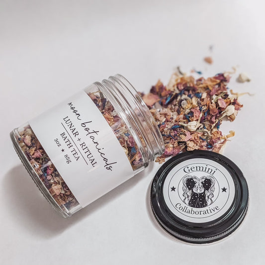 Photo of nine ounce glass jar with  bath tea made of dried florals and bath salt salts spilling out.