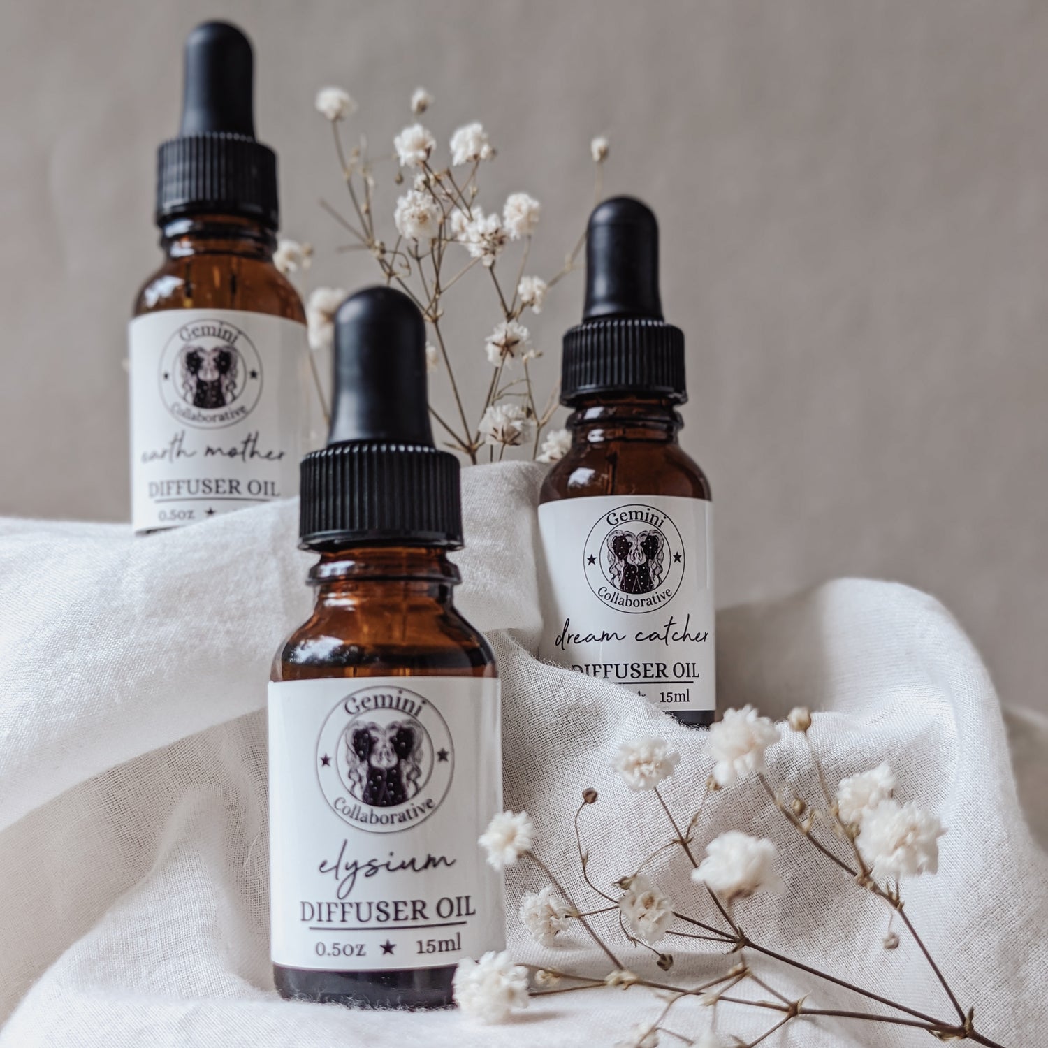 Photo of three half ounce glass bottles of diffuser oils arranged in front of dried florals 