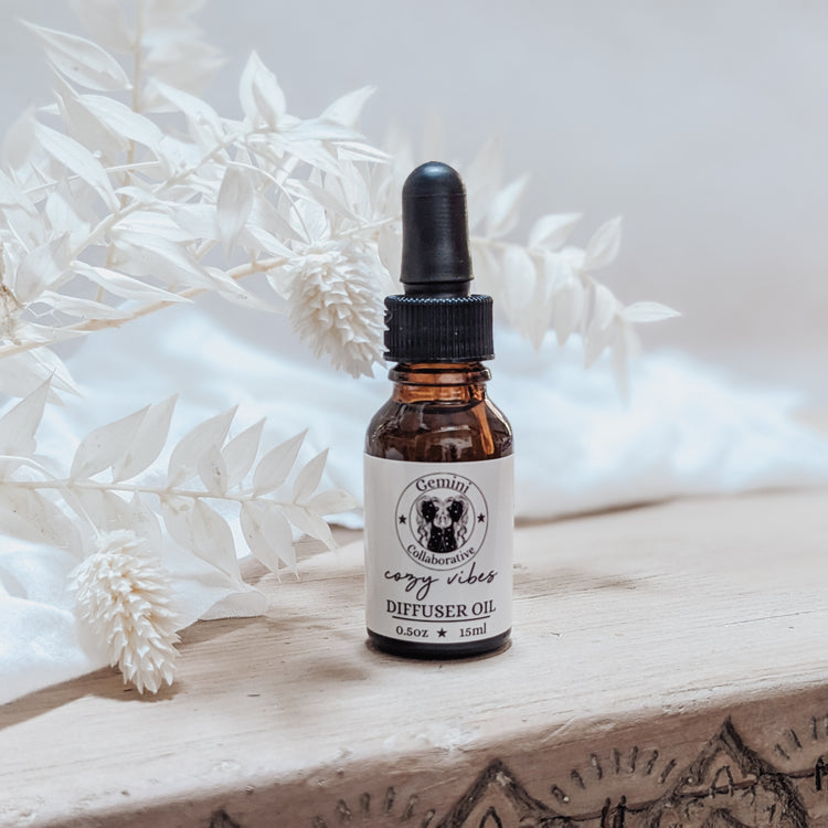 Photo of diffuser oil in half ounce glass bottle with glass pipette in front of floral arrangement