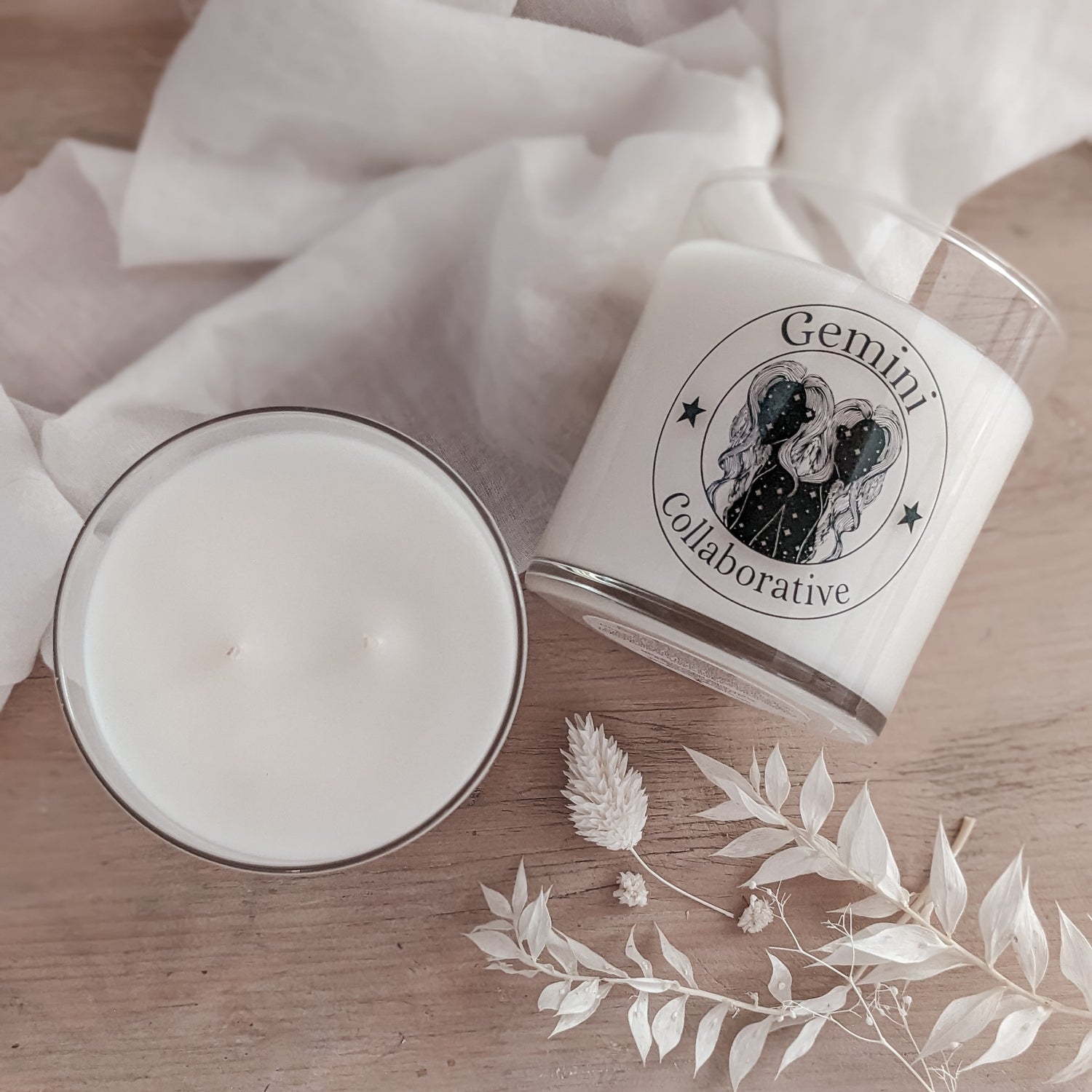 Photo of two candles, one on its side and one from the top showing double wicks with florals in the background.